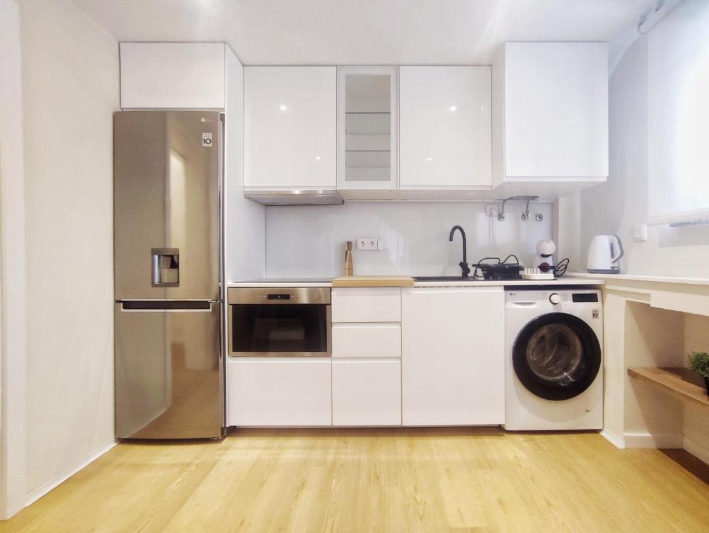 eine Küche mit weißen Schränken und einem Edelstahlkühlschrank in der Unterkunft Casa Náutica T1 Norte in Ovar