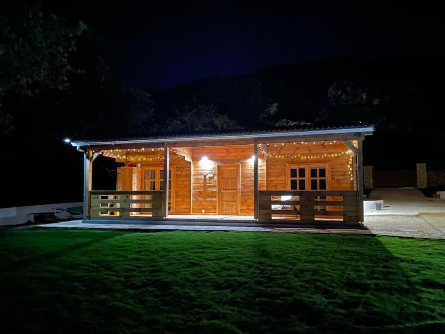 a log cabin at night with a green lawn at The Retreat - Oak Lodge in Corfu