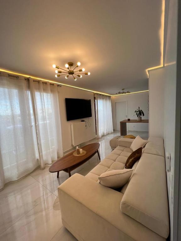 un salon avec un canapé blanc et une télévision dans l'établissement Appartement de Luxe, à Villepinte