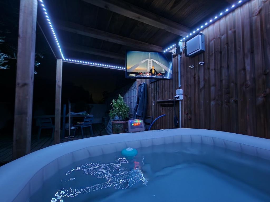 un jacuzzi dans une pièce avec une télévision et des lumières dans l'établissement Au Douni - Jacuzzi, jardin, parking couvert et bureau équipé, à Aubais