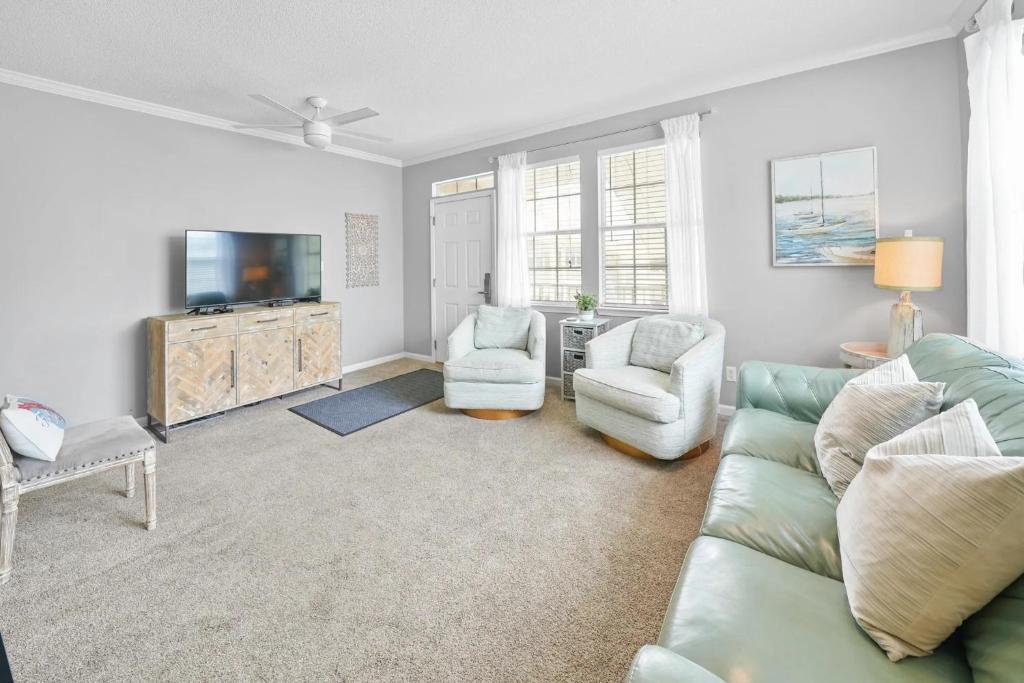 ein Wohnzimmer mit einem Sofa und zwei Sesseln und einem Fernseher in der Unterkunft Sunny escape in Miramar Beach in Destin
