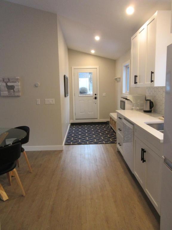 a kitchen with white cabinets and a table and a door at Mountain View Bed & Breakfast in Banff