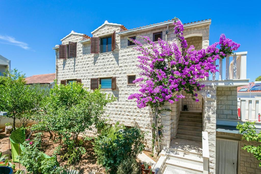 a house with purple flowers in front of it at Apartments with parking space Supetar, Brac - 5670 in Supetar