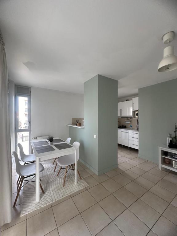 une cuisine blanche avec une table et des chaises dans une pièce dans l'établissement Soleil de Lyon - Appartement lumineux au centre-ville, à Lyon