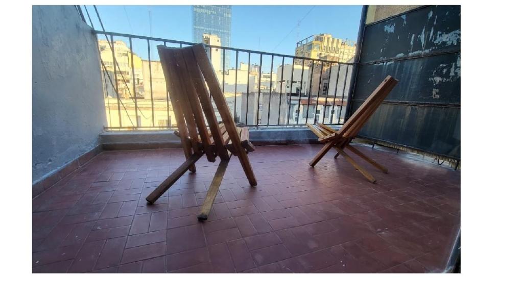 un par de sillas de madera sentadas en un balcón en Luminoso y Cálido con Balcón a la calle, en Buenos Aires