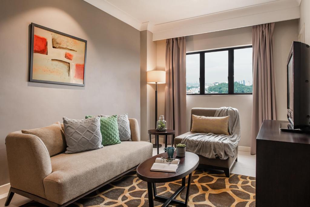 A softly styled living room has a sofa, lounge chair, television and a city-facing window.