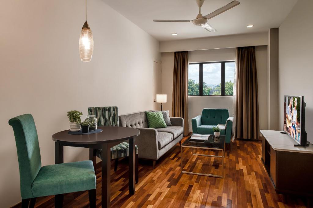 A larger living-and-dining room with polished wood flooring, a dining table and several upholstered seats.