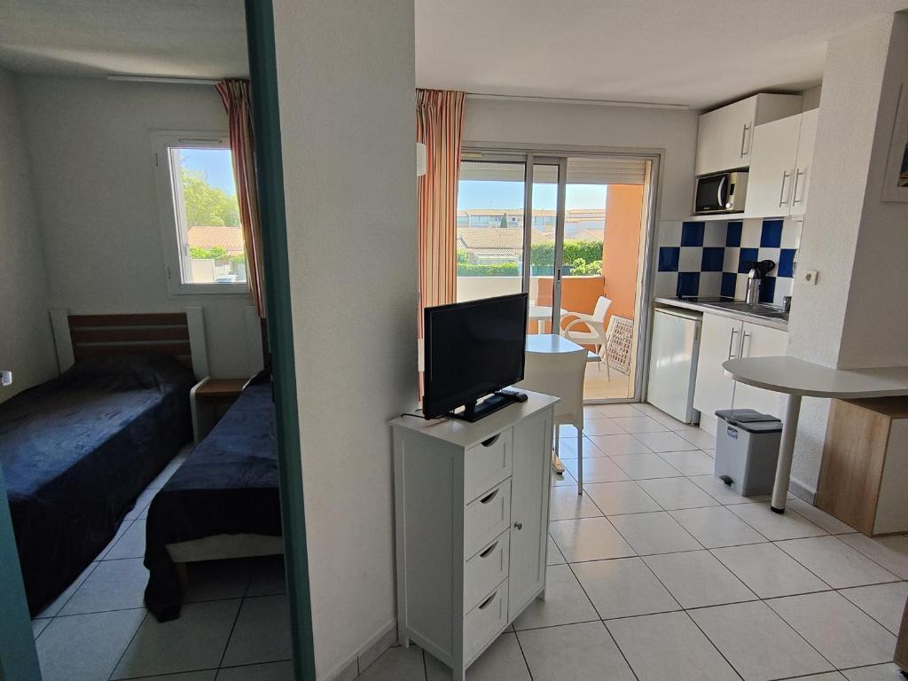 Cette chambre comprend un lit, une télévision et une cuisine. dans l'établissement Appartement Bord de Mer - Climatisation, Balcon, Parking et Piscine - FR-1-801-3, au Cap d'Agde