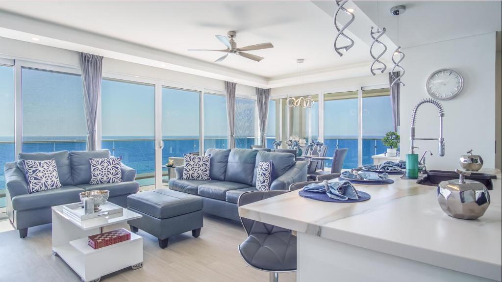 a living room with blue furniture and large windows at Encantame Towers -VERANO 2105-Luxury Beachfront Condo in Playa Encanto