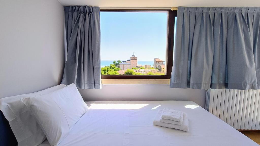 a bedroom with a white bed with a window at Attico Novecento in Porto San Giorgio