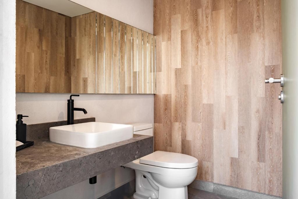 a bathroom with a white toilet and a sink at Casa Cibeles by Lumina in Mexico City
