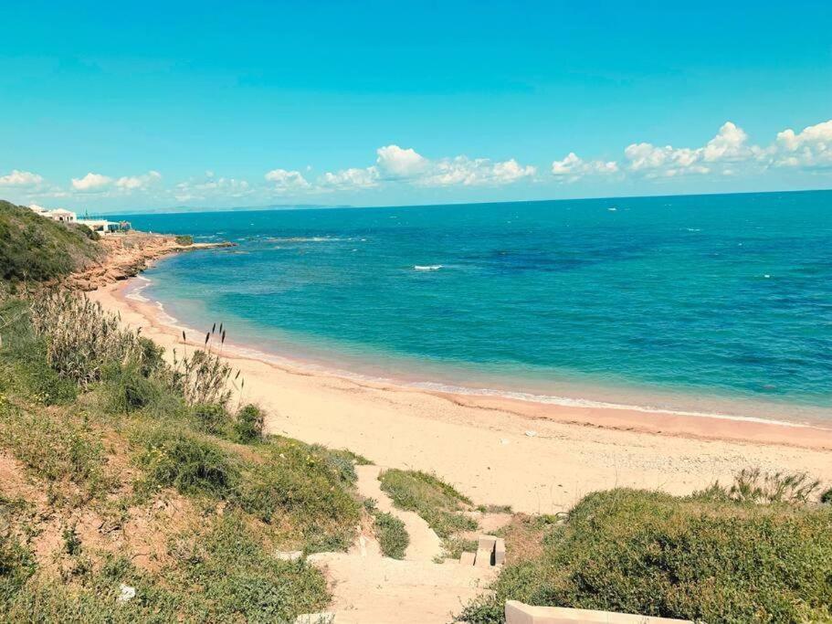 una spiaggia con persone che camminano sulla sabbia e sull'oceano di Luxurious Sea View with Private Beach in Gammarth, Marsa a Gammarth