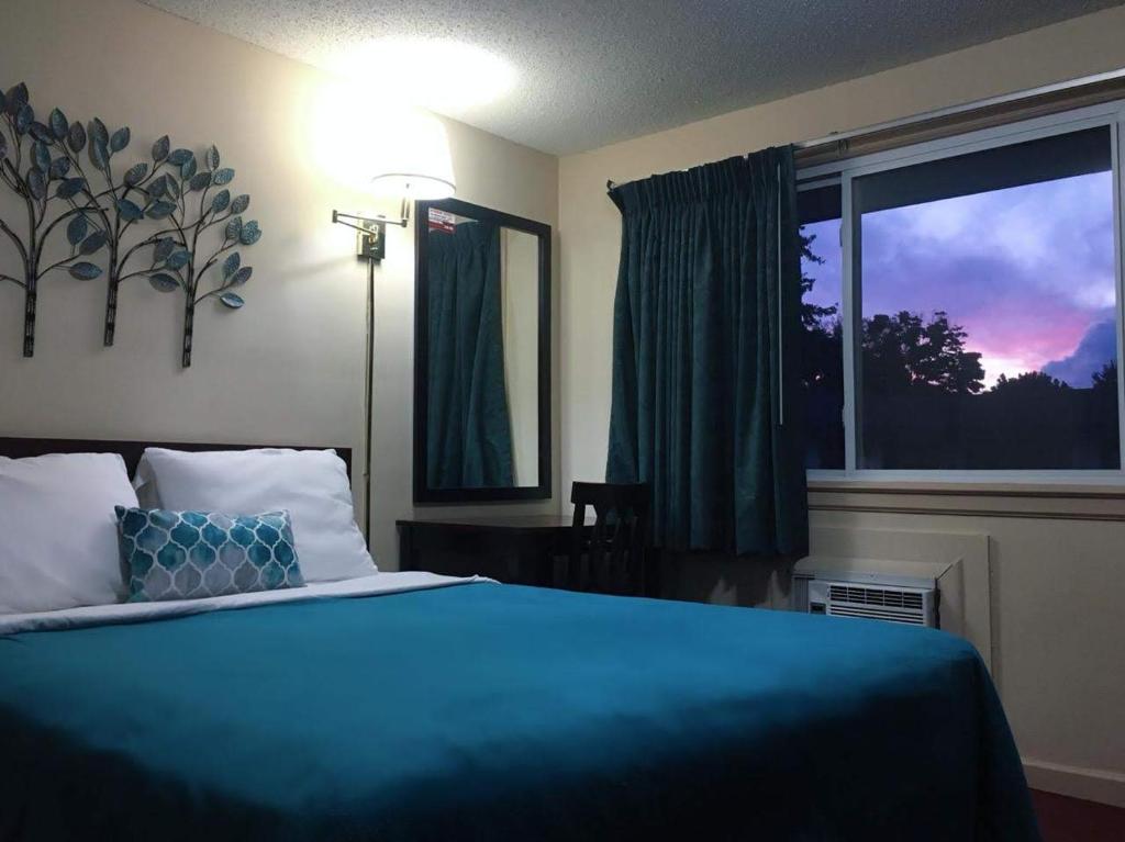a bedroom with a blue bed and a window at Swiss Cottage Inn in Niagara Falls