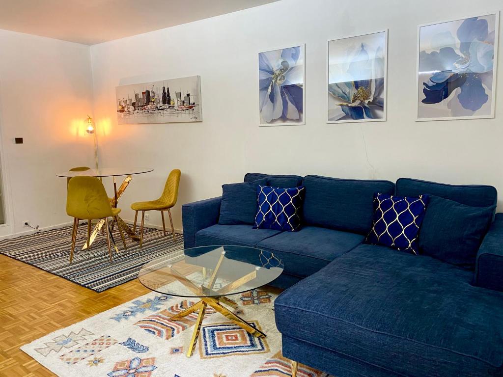 un salon avec un canapé bleu et une table dans l'établissement Appartement spacieux Paris Vanves Parc des expositions, à Vanves