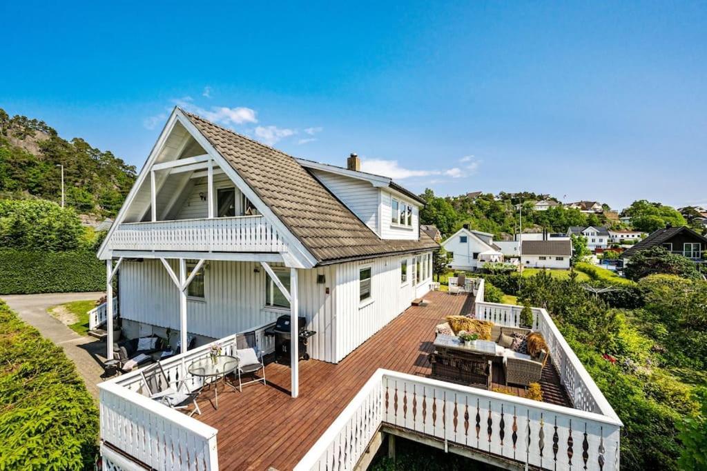 a large white house with a large deck at Koselig hus rett ved stranda,nydelig & ferierende! in Grimstad