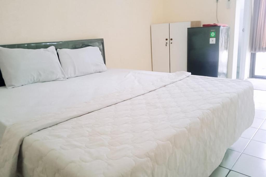 ein großes weißes Bett mit weißer Bettwäsche und Kissen in der Unterkunft RedLiving Apartemen kemang View - My Room LapanLapan Tower Mahagoni in Pekayon Satu