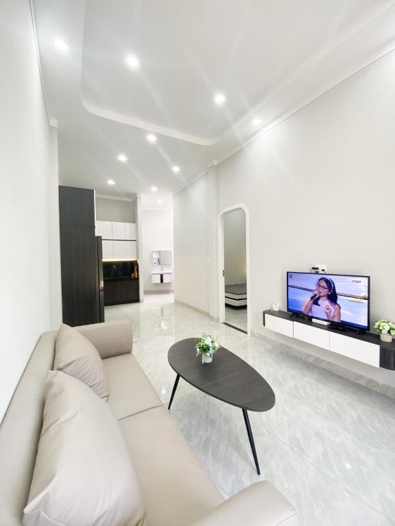 a white living room with a couch and a table at Hidden Bungalow in Buôn Enao