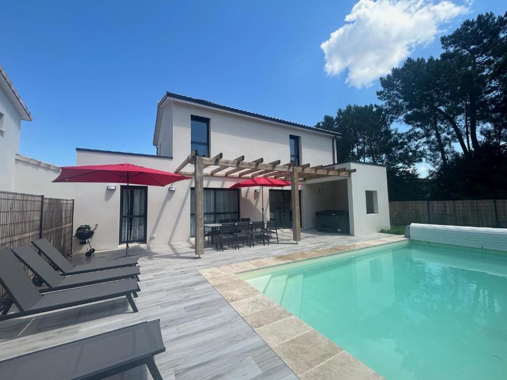 a house with a swimming pool and a patio with umbrellas at La Forêt d'Armotte villa 19 in Saint-Augustin