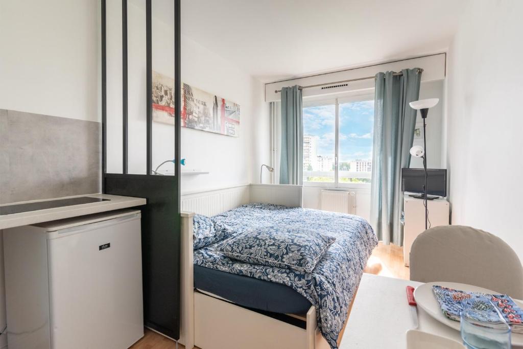 ein kleines Schlafzimmer mit einem Bett und einem Tisch in der Unterkunft Le Ptit Henri - Studio à 20min de Paris in LʼHay-les-Roses