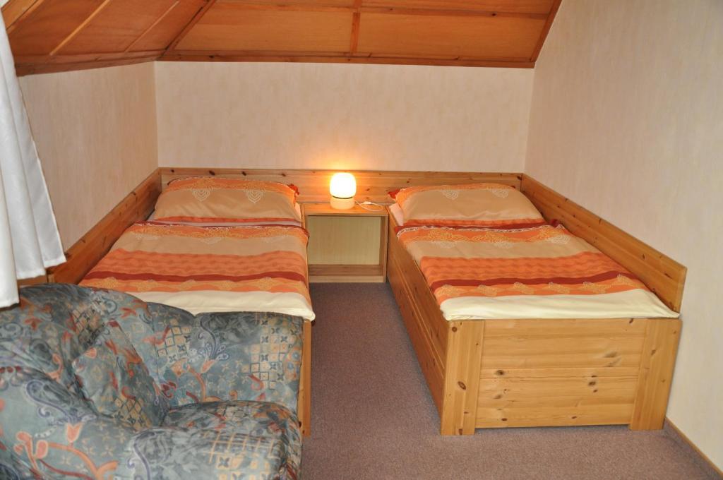 ベロウンにあるPension Nostalgieのベッド2台とソファが備わる小さな客室です。
