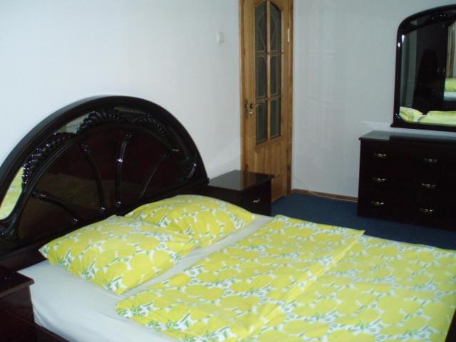 Cama con almohada amarilla y cómoda en Marijos Karpenko Apartaments en Kaunas