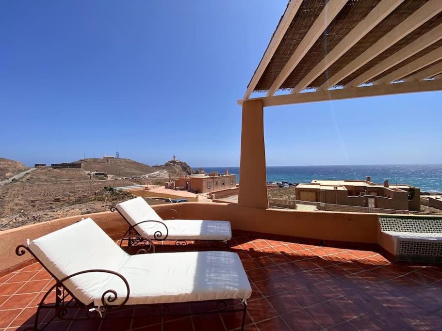 a patio with white chairs and a view of the ocean at Casa de la Media Luna in El Pozo del Cabo