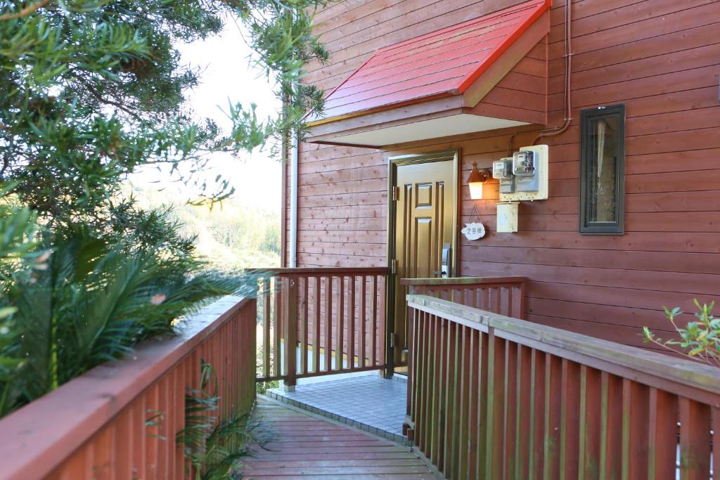 a red house with a wooden walkway to the front door at Farm Inn Minamiboso in Minamiboso