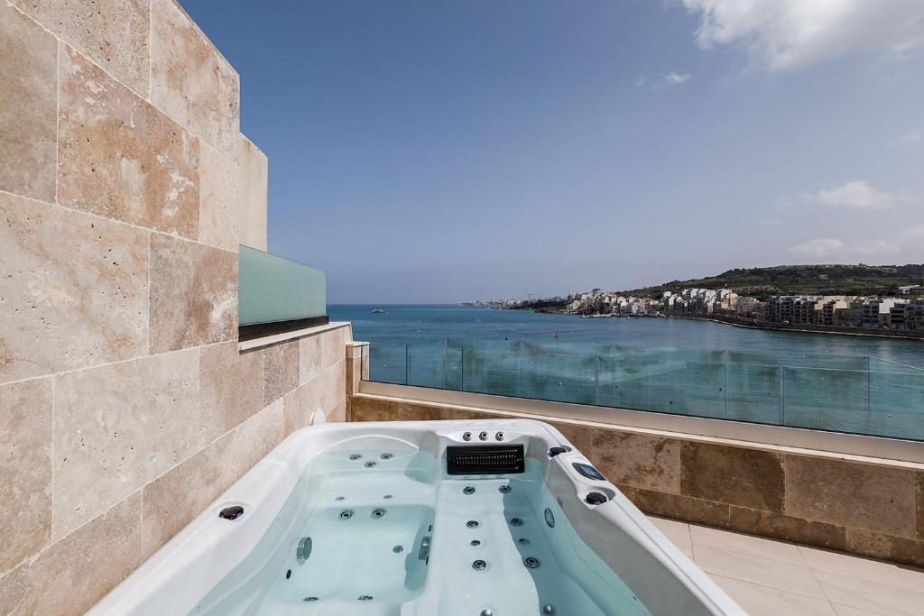 a bath tub on a balcony with a view of the water at DuplexPenthouse seafront with hot tub by Homely in St. Paul's Bay