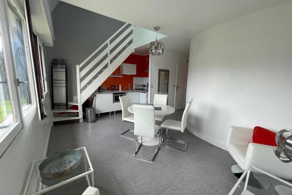 une salle à manger avec des chaises blanches et un escalier dans l'établissement Nice 2 rooms near Gare de Trouville - Deauville, à Trouville-sur-Mer