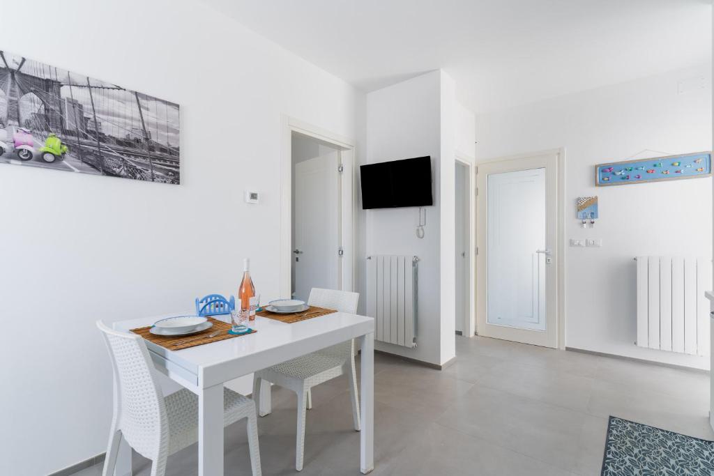 a white dining room with a white table and chairs at Dimora Conchiglie in Corsano