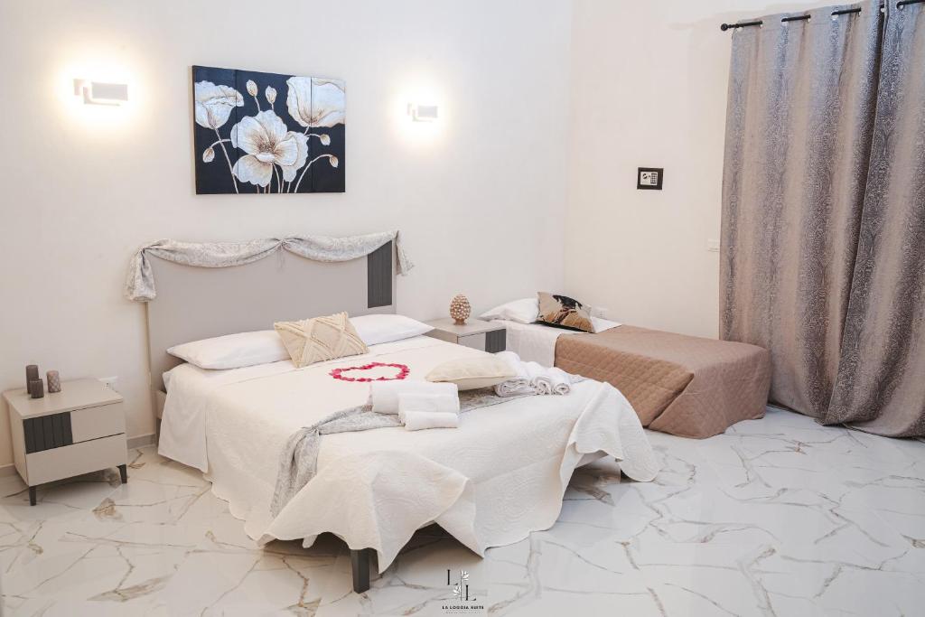 a bedroom with two beds and a painting on the wall at La Loggia Suite in Marsala