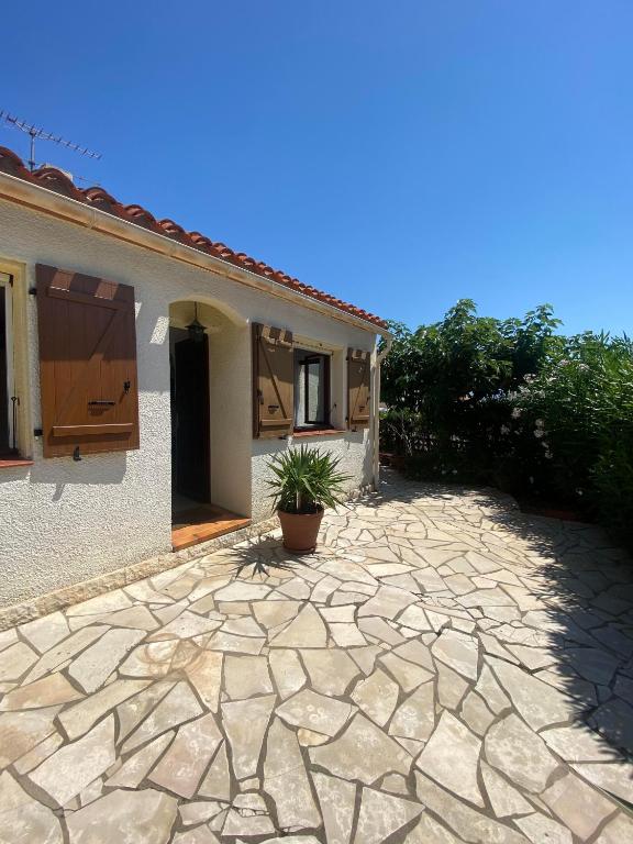 une maison avec une plante en pot sur une allée en pierre dans l'établissement Maison 6 personnes au calme 6MERL10, à Canet