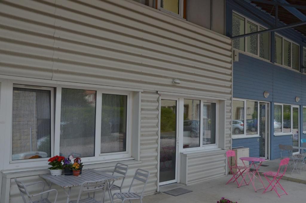 un patio avec une table et des chaises à côté d'un bâtiment dans l'établissement Le Prieure Valette, à Hérouville-Saint-Clair