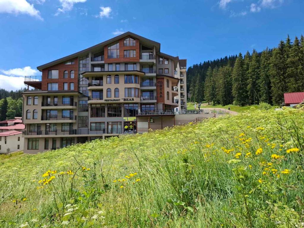 a large building on a hill with a field of flowers at The Bear Pamporovo in Pamporovo