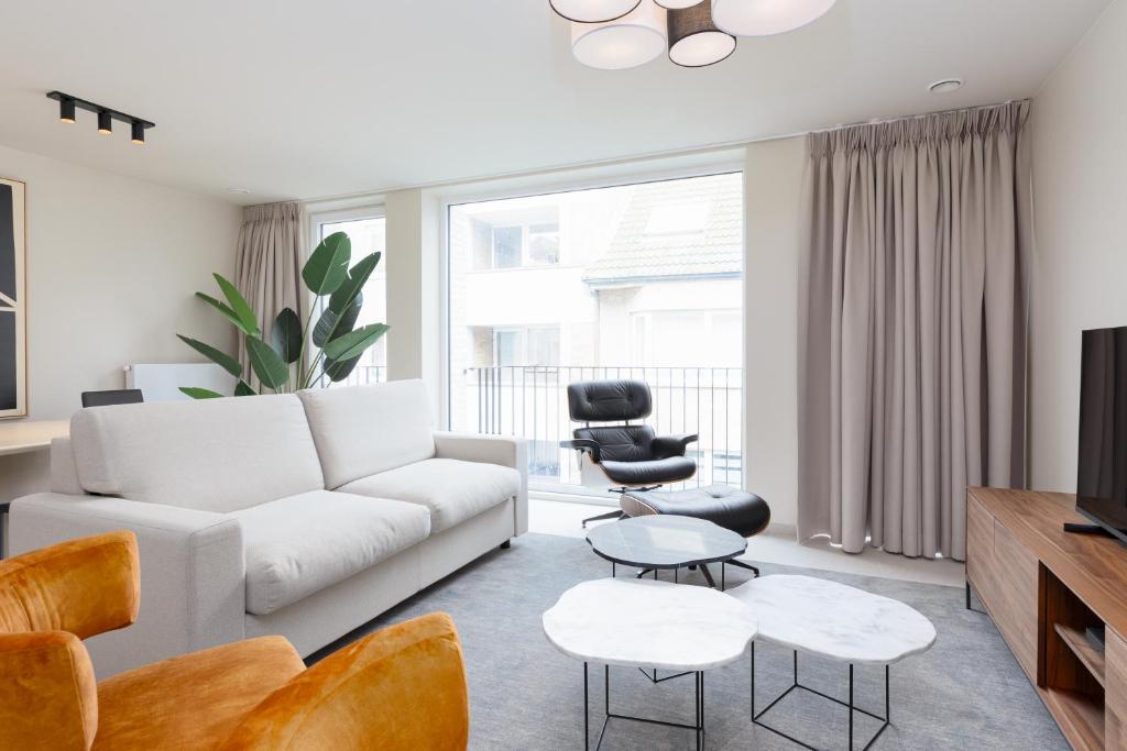 Una sala de estar con un sofá blanco y sillas. en Kaaiman Ostend - Casselbergh Residences, en Ostende