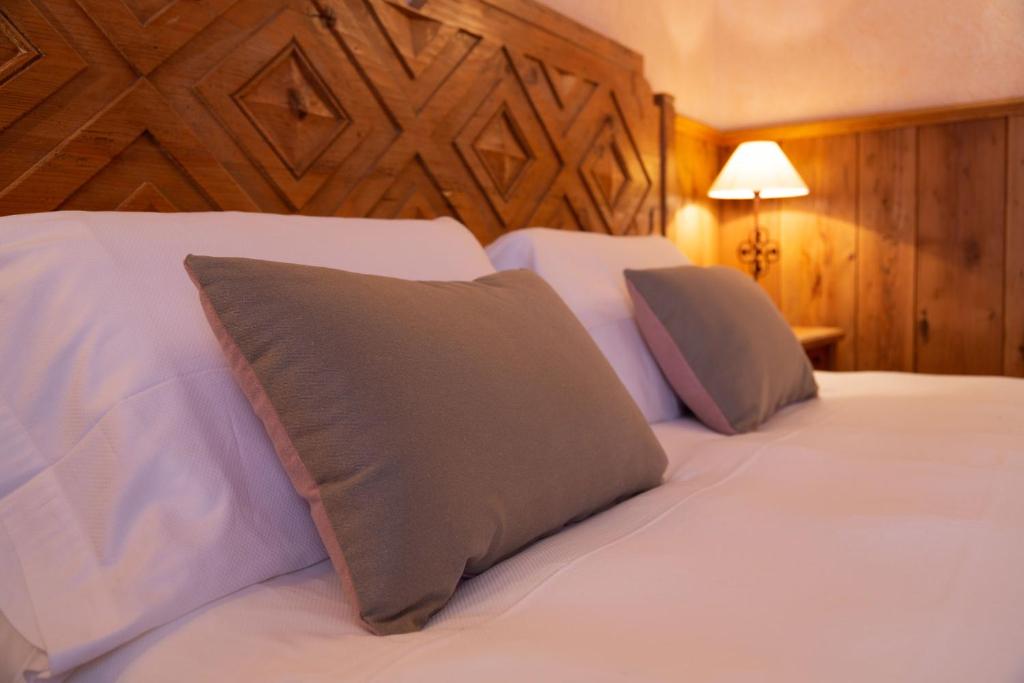 a bedroom with two beds with white sheets and pillows at Hotel Bouton d'Or - Courmayeur in Courmayeur