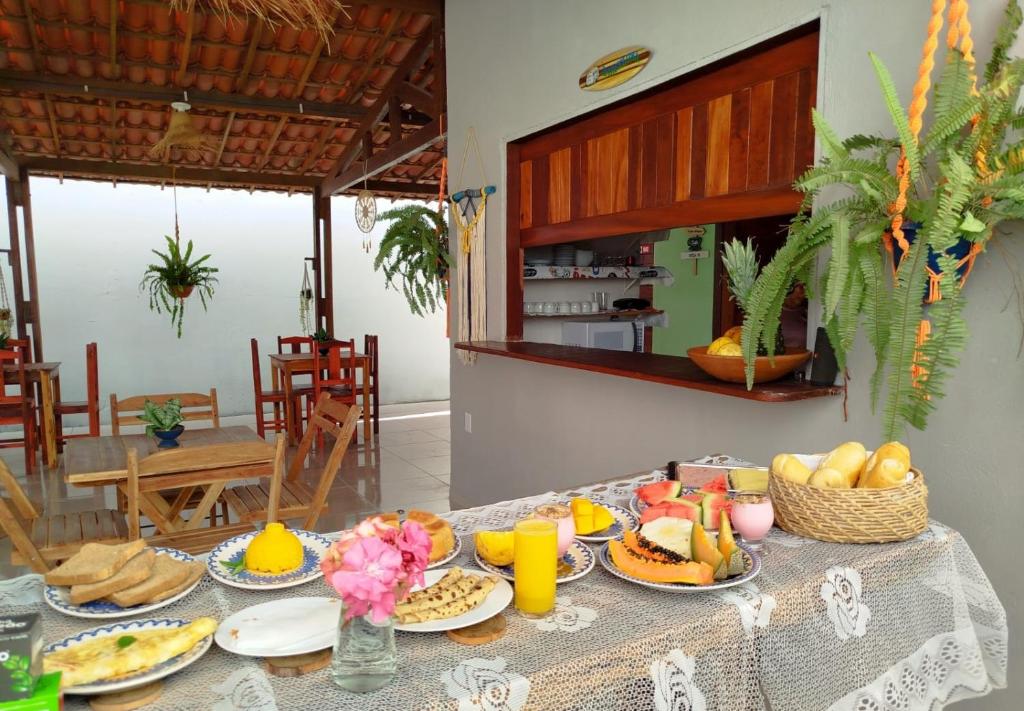 a table topped with plates of food and orange juice at Côco Verde - Pousada Icaraí Kite Village in Icaraí