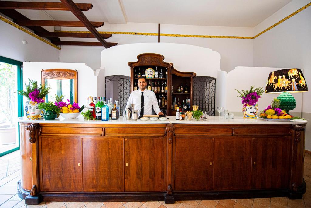 a bartender standing behind a bar in a room at Baia Taormina - CDSHotels in Forza dʼAgro