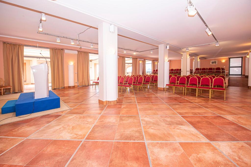 a large room with red chairs and a stage in the middle at Baia Taormina - CDSHotels in Forza dʼAgro