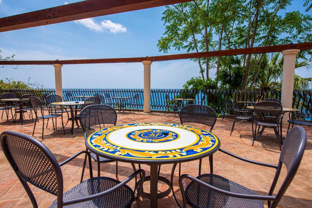a patio with tables and chairs and a table with a plate on it at Baia Taormina - CDSHotels in Forza dʼAgro