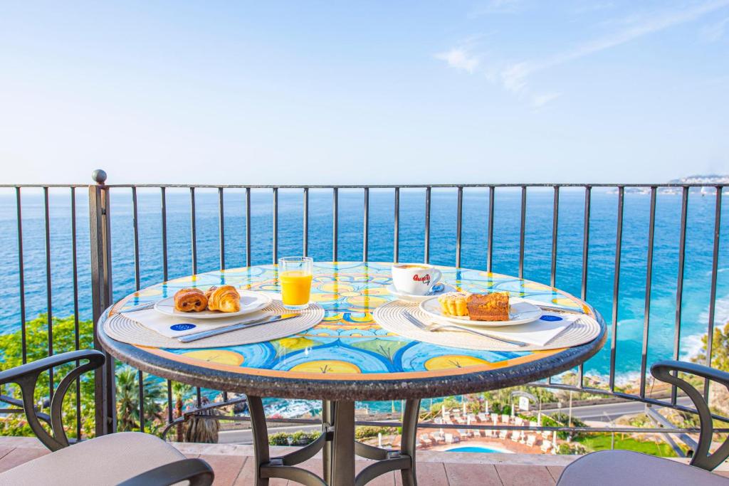 a table with food and drinks on a balcony overlooking the ocean at Baia Taormina - CDSHotels in Forza dʼAgro