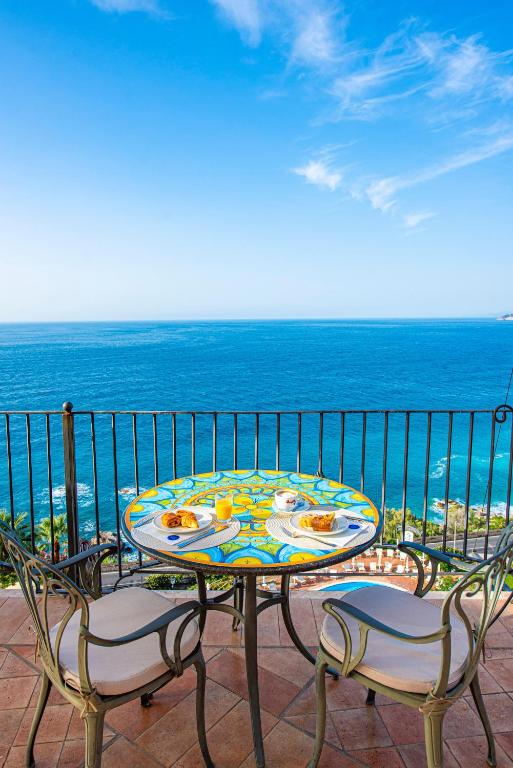 a table and chairs on a balcony with the ocean at Baia Taormina - CDSHotels in Forza dʼAgro