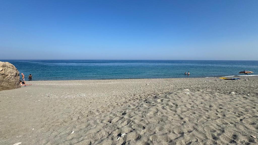 a sandy beach with people on the water at Baia Taormina - CDSHotels in Forza dʼAgro