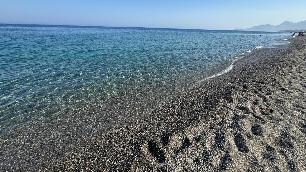a beach with footprints in the sand and water at Baia Taormina - CDSHotels in Forza dʼAgro