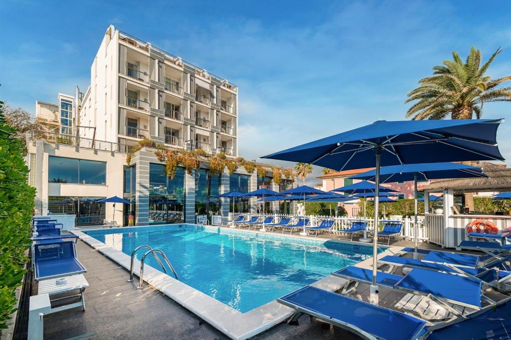 a pool with chairs and umbrellas next to a building at Hotel Excelsior in Marina di Massa