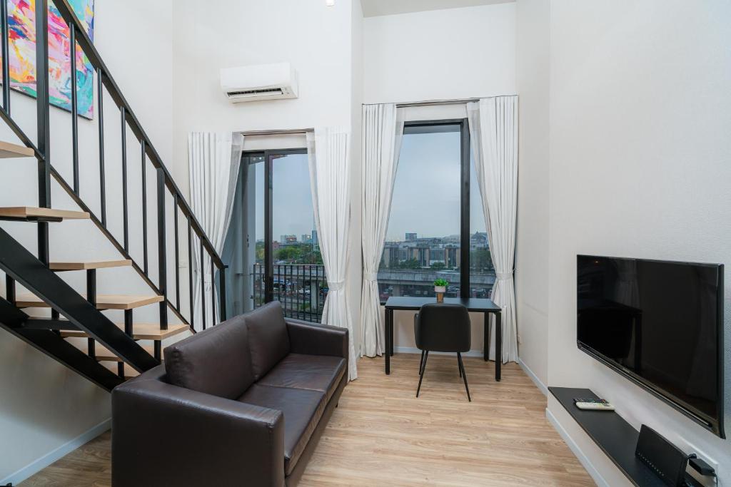 A split-level room with a sofa, television, work desk and city-facing windows.