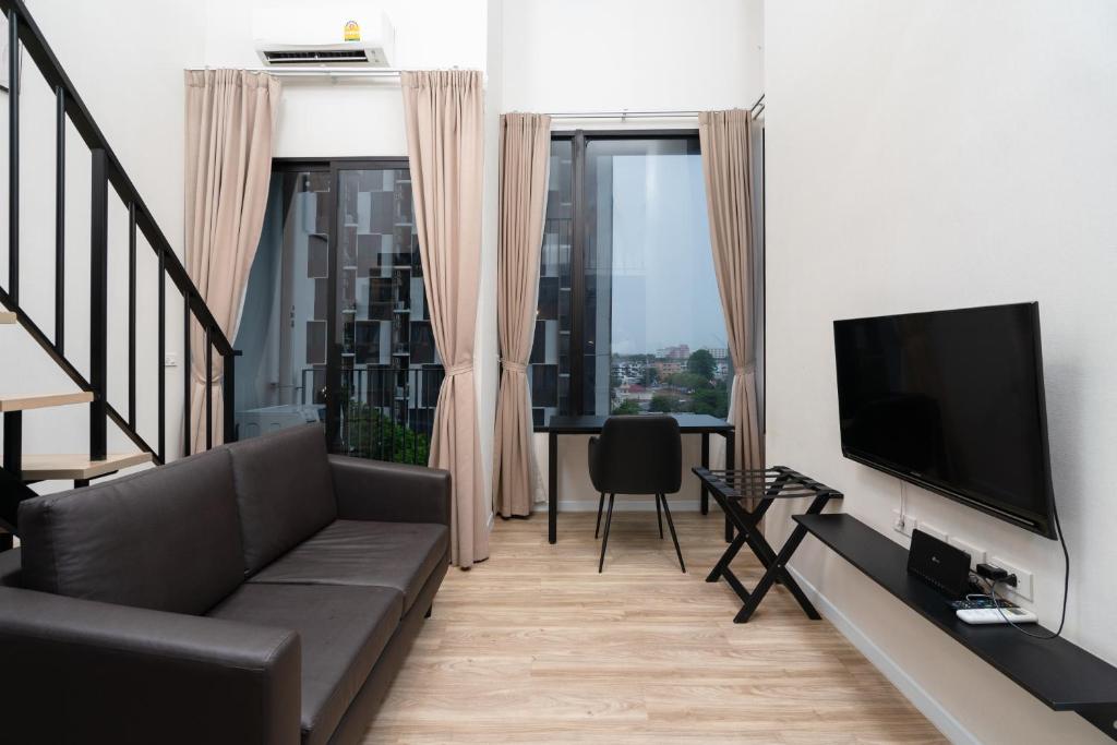 A split-level sitting area with a sofa, TV, small dining desk, and tall windows.