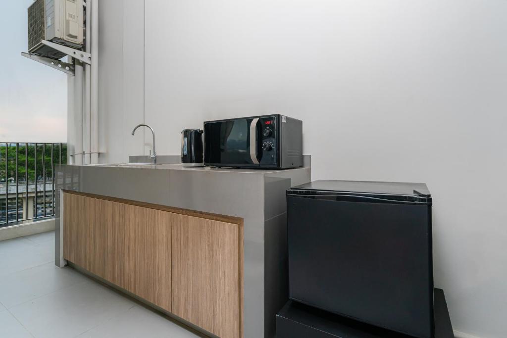 A compact in-room kitchenette with a microwave, mini-fridge, sink and balcony beyond.