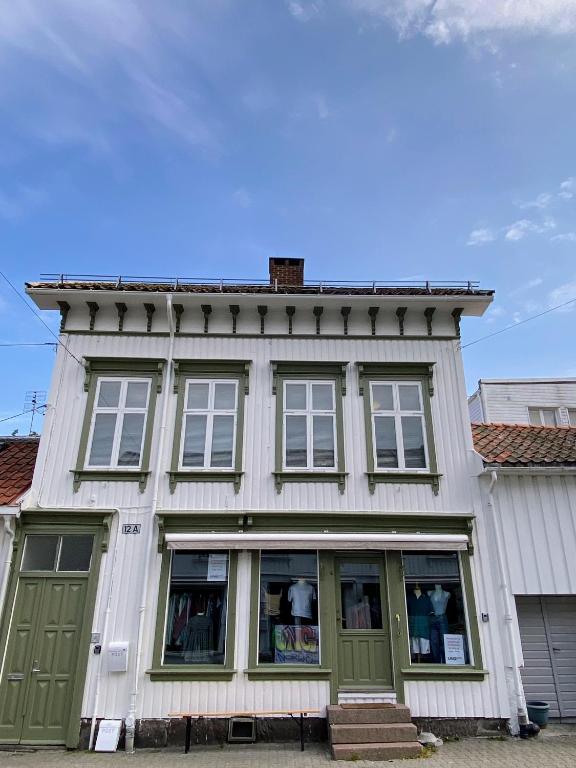 a white building with green doors and windows at Sjarmerende leilighet i hjertet av Risør in Risør