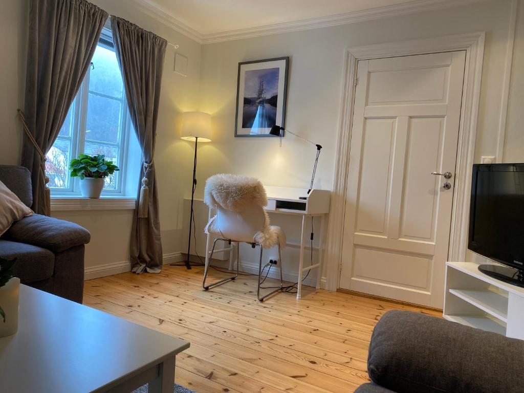 a living room with a white chair and a desk at Sjarmerende leilighet i hjertet av Risør in Risør